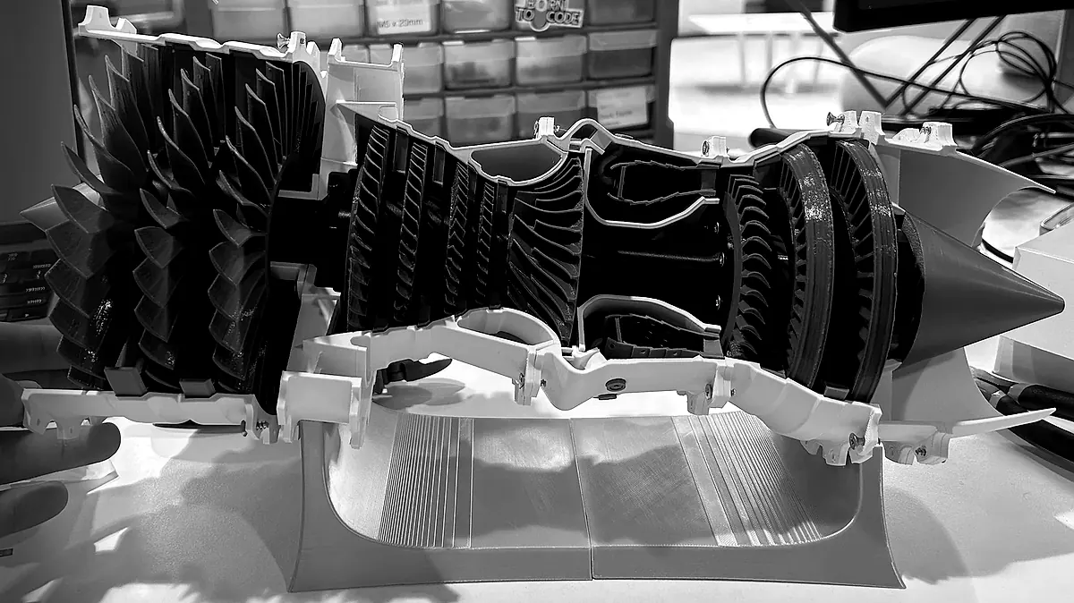 Black-and-white photo of BatLabs’ 3D-printed turbofan cutaway model on its stand on the workshop bench.